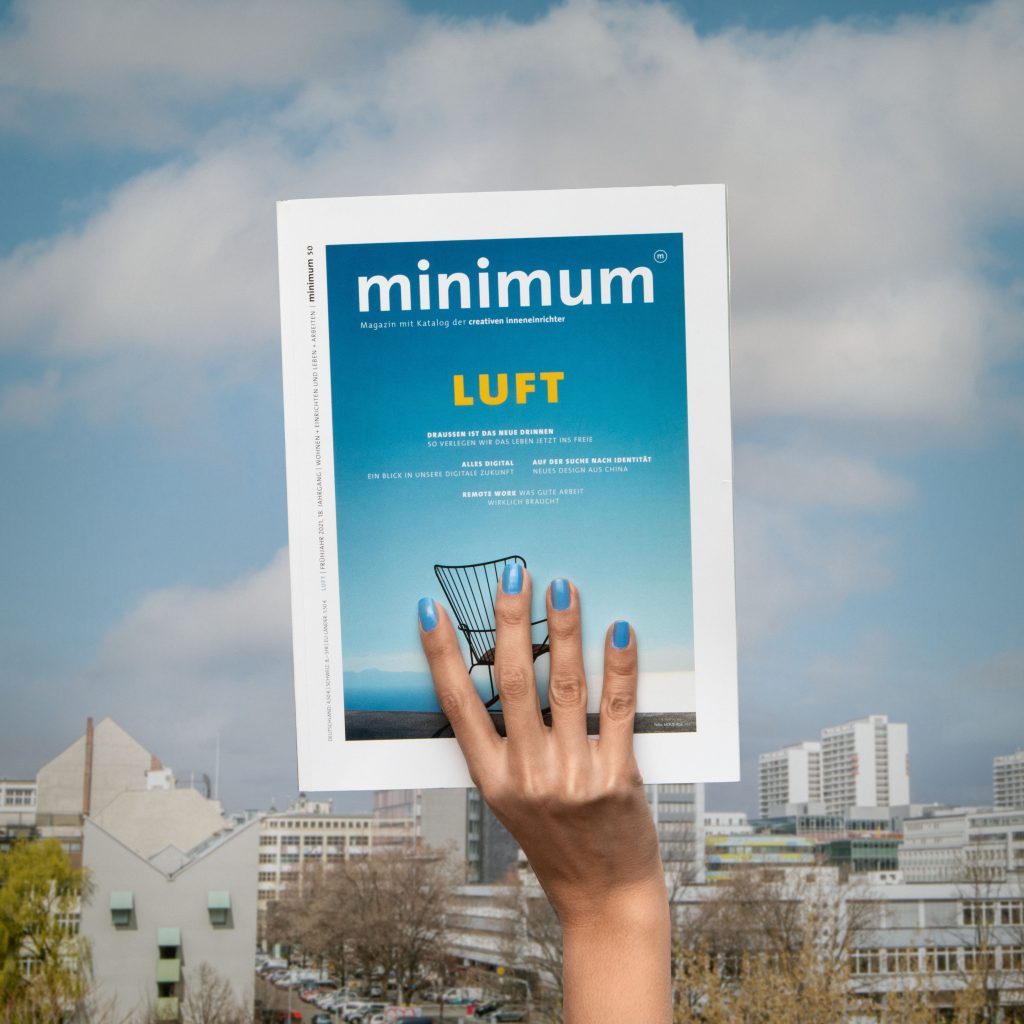 Vor der Berliner Skyline hält eine Hand das minimum Magazin der Creativen Inneneinrichter in die Höhe.